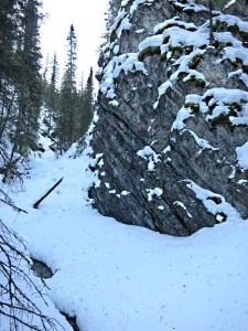 The path drops onto the stream itself with holes in the snow where the water can be seen rushing below