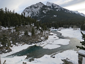 More open water than usual in winter below the falls seen from the top of the crag alongside, Mount Rundle towering above