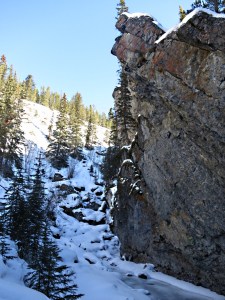 "a vertical rock face towered on the right, narrow ledges picked out in white"