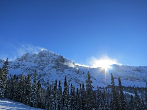 Even though it’s midday, as I drop down the run the sun drops behind the ridge with strong wind blowing loose snow off it