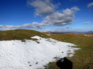 Snow ablated by sun and wind, small cumulus cloud marking the curving edge of the ridge 