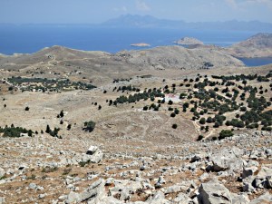 Steep rocky drop to the mid-level  plateau and the Roukouniotis fortress monastery, Turkey in the distance looming large