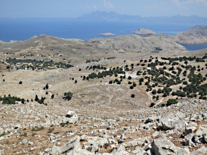 Steep rocky drop to the mid-level  plateau and the Roukouniotis fortress monastery, Turkey in the distance looming large