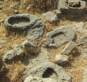 A scatter of carved stone bowls and the top of a cistern alongside.