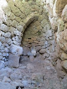 At the top of the col between the main caldera and the Evangelistra monastery, climb over unstable rocks to three dwellings almost completely hidden and at the back is a small ‘chapel’ with a shard of sculpted marble on a small altar.